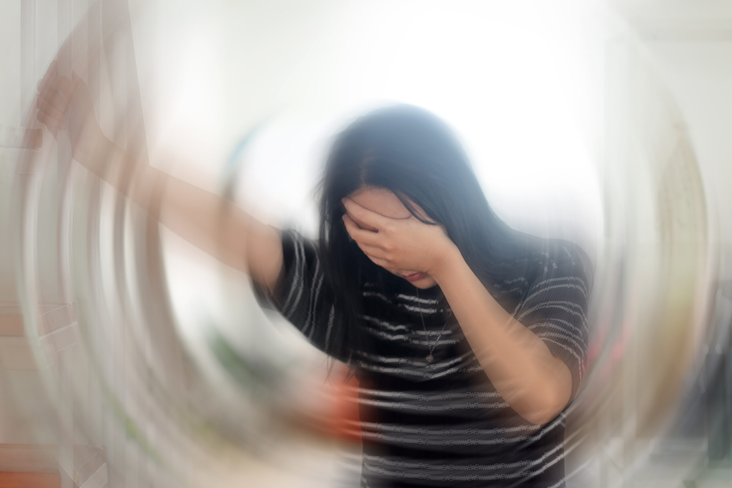 Γυναίκα με το χέρι στο κεφάλι, με οπτικό εφέ περιστροφής στο περιβάλλον.